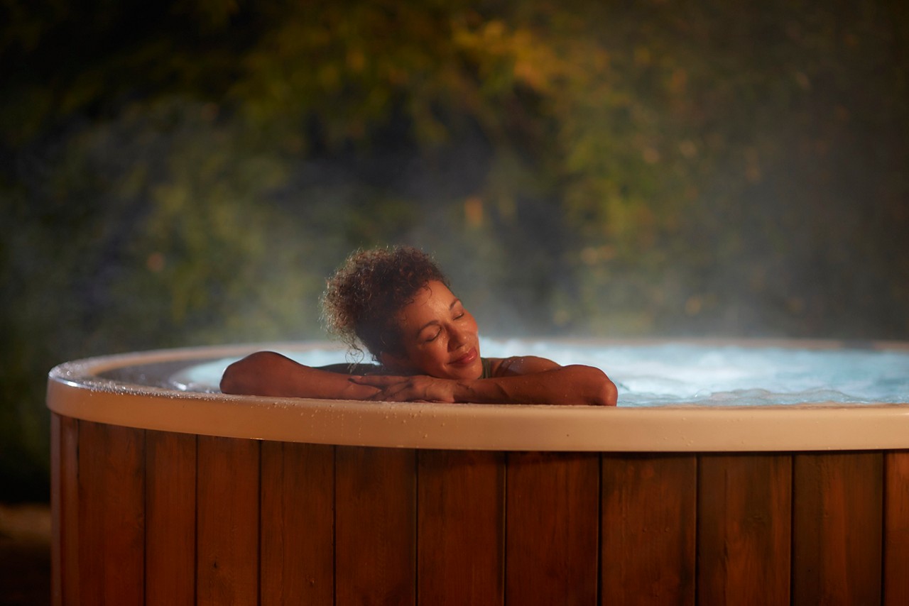 Woman soaking in a bubbling outdoor hot tub.